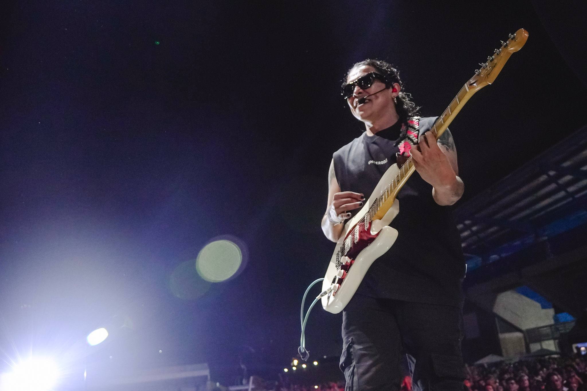 Johan Villamil con su guitarra blanca, bajo luces azules y violetas, en Ibagué Ciudad Rock XXV
