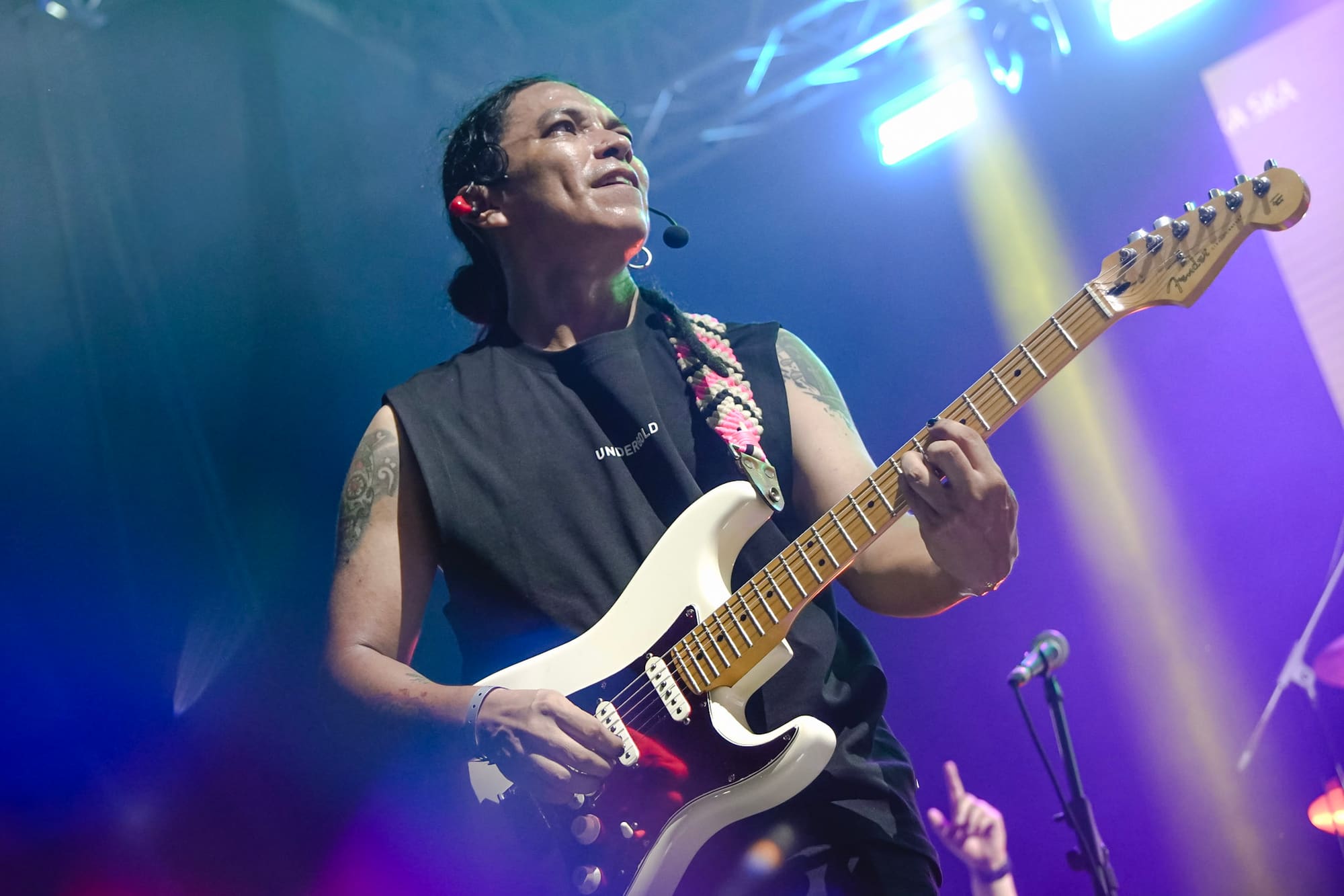 Johan Villamil toca su guitarra blanca bajo luces azules y violetas